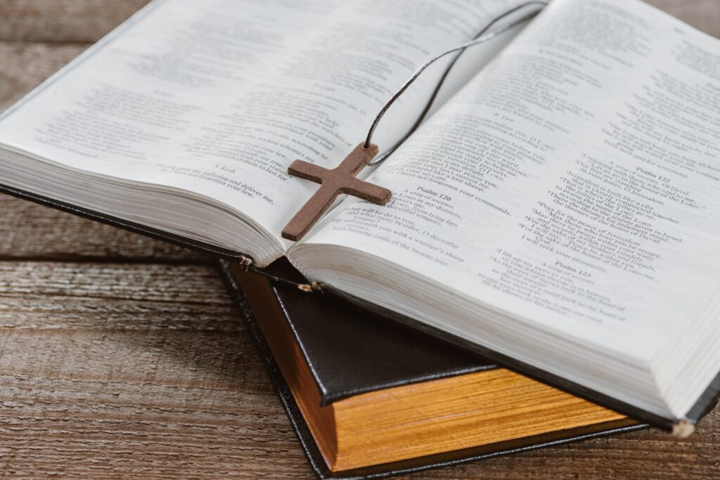 Picture shows a small cross laying across some pages of the Bible.